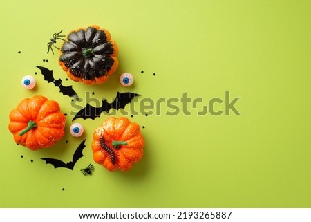 Halloween concept. Top view photo of pumpkins bat silhouettes creepy eyes spiders centipede and star shaped confetti confetti on isolated light green background with copyspace