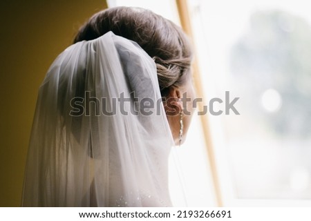 photo of the bride from the back close-up, wedding white veil, the bride is standing by the window