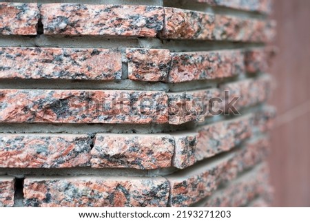 The facade of the house is decorated with decorative facade red stone, close up, selective focus. Facade decorative stone Royalty-Free Stock Photo #2193271203