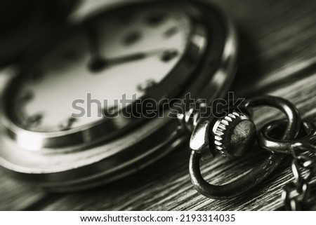 Vintage pocket watch on a wooden background, black and white photo. A vintage mechanical watch close up. Concept of passing time. Concept of old age. 