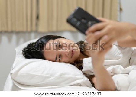 Asia woman using a smart phone in the morning on the bed.