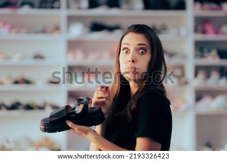 
Outraged Woman Checking Price Tag on a Shoe in the Footwear Store. Stressed customer being broke looking for cheaper offers
