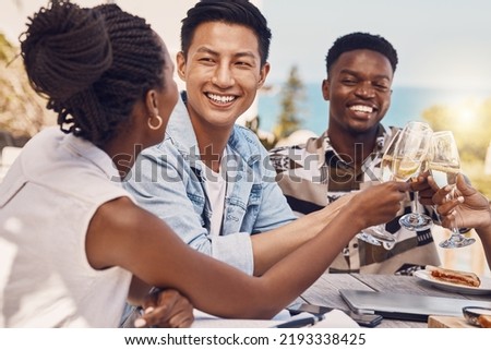 Diverse group toasting and celebrating friendship at an outdoor restaurant, having fun and laughing. Happy people cheers while bonding, talking and enjoying a celebration of good, exciting news