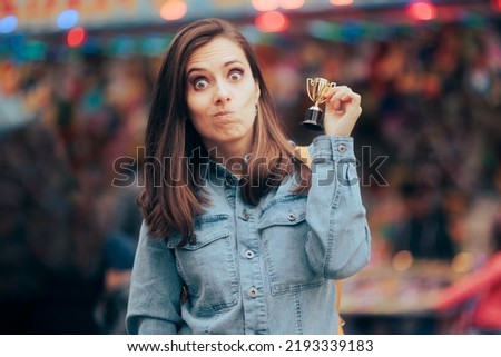 
Funny Woman Winning a Small Trophy at Funfair Contest. Sore loser receiving a participation consolation prize
 Royalty-Free Stock Photo #2193339183