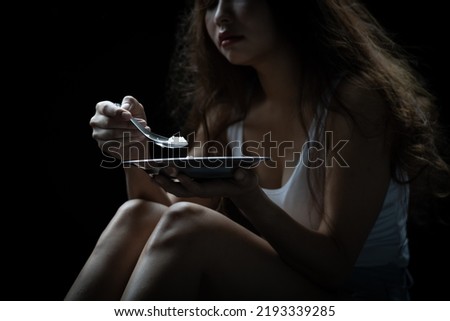 Homeless. Homeless woman eating food in the dark light of the building corner Royalty-Free Stock Photo #2193339285