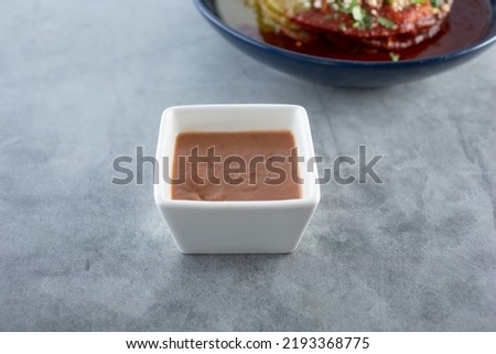 A view of a square condiment cup of refried beans, as a side dish.