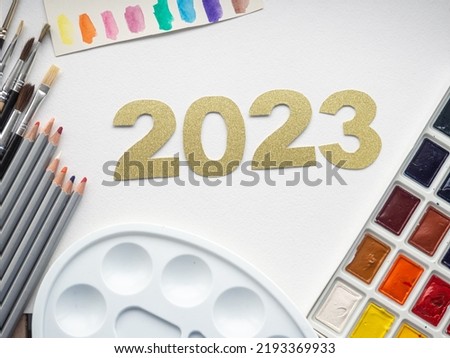 2023 greeting card. Place for text with paints, palette, pencils and brushes. The concept of goals in painting. Happy New Year, Merry Christmas. Education motivation, inspiration. Top view, flat lay