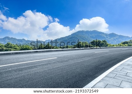 Asphalt road and green forest with mountain background