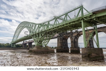Silver Jubilee Bridge and Runcorn Railway Bridge pictured at low tide from the banks of the River Mersey in Cheshire.