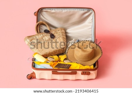 Suitcase with clothes, beach accessories and passport on pink background Royalty-Free Stock Photo #2193406415