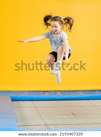Happy little girl jumping on trampoline in fitness center Royalty-Free Stock Photo #2193407339