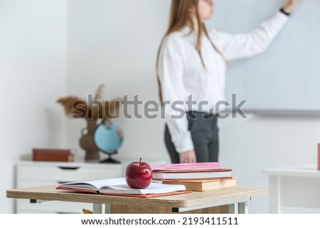 Apple with school books on table in classroom