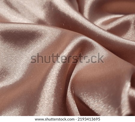 Wavy beige silk fabric in folds (macro, texture).