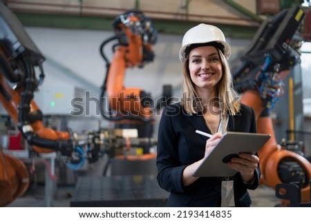 Female chief engineer in modern industrial factory using tablet and making audit.