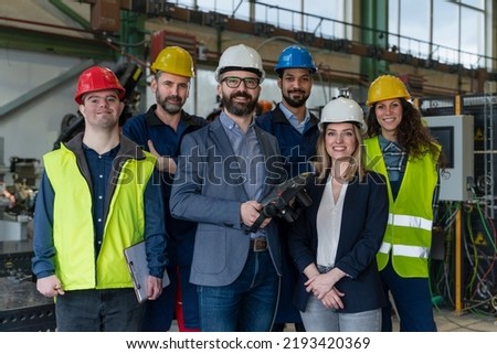 Young man worker with Down syndrome with manager and other collegues working in industrial factory, social integration concept. Royalty-Free Stock Photo #2193420369