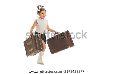 One beautiful little girl, happy kid running with retro suitcases isolated on white studio background. Retro vintage style concept. Holidays, vacation, trip. Concept of child emotions, facial