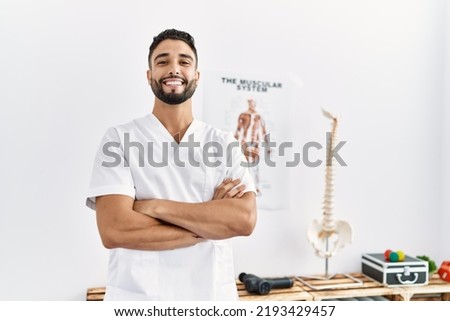Young arab man wearing physiotherapist uniform standing with arms crossed gesture at clinic Royalty-Free Stock Photo #2193429457