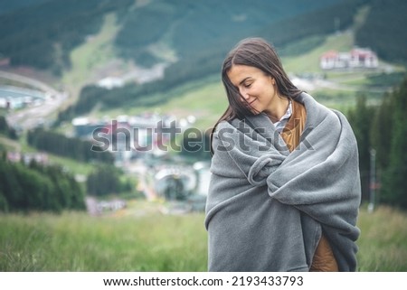 A young woman wrapped in a blanket in the mountains. Royalty-Free Stock Photo #2193433793
