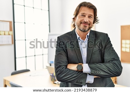 Middle age caucasian man smiling confident with arms crossed gesture at office Royalty-Free Stock Photo #2193438879