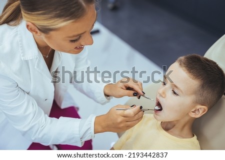 Little boy having regular dental check-up. Cute boy smiling while teeth exam . Happy boy sitting in dentists chair and having check up teeth. Portrait of smiling little boy sitting in dental chair