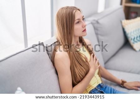 Young caucasian woman suffering for pain chest sitting on sofa at home
