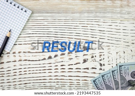 RESULT - word (text) and dollars on a white wooden table, notebook, notepad. Business concept: buying, selling, commerce (copy space).