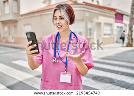 Young caucasian doctor woman having video call using smartphone at the city.