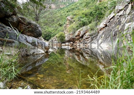 Rocks and reflections in T.P Kota waterfalls at Andhra Pradesh, India. Mountain reflection in still water with green trees.