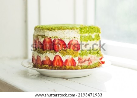 Fraisier cake with fresh summer strawberry, spinach green sponge and white diplomat cream on bright vintage background. Cut slice view. Blurry background. Free copy space. French dessert