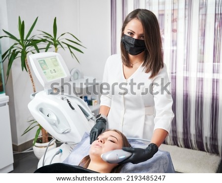 Specialist in the field of aesthetic medicine performing ultrasonic non-surgical facelift procedure for woman. SMAS lifting - great alternative to plastic surgery. Royalty-Free Stock Photo #2193485247