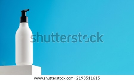 Mockup of a white dispenser with a cosmetic product with a place for your logo on a podium on a blue background.