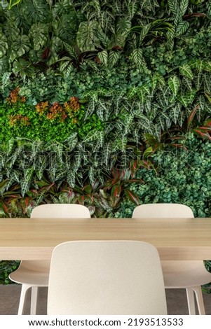 Green living room with chairs and table, vertical garden - stock photo