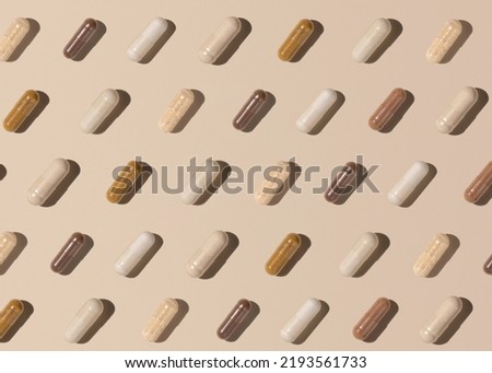 Capsules on light beige top view, hard shadows, creative pattern. Preventive medicine and healthcare, taking dietary supplements and vitamins.  Assorted pharmaceutical medicine capsules Royalty-Free Stock Photo #2193561733