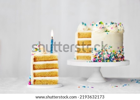 Sliced birthday cake with blue birthday candle and colorful sprinkles