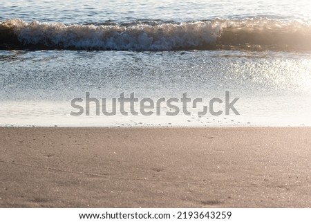 Sunlit Waves Crashing onto The Beach at Daybreak Royalty-Free Stock Photo #2193643259