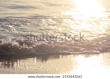 Sunlit Waves Crashing onto The Beach at Daybreak Royalty-Free Stock Photo #2193643261