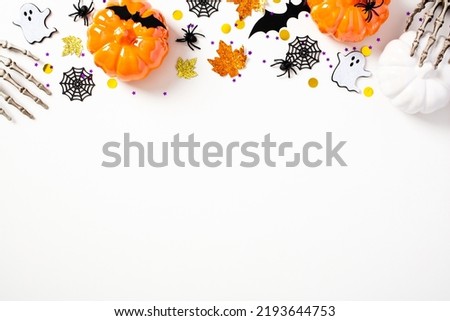 Happy Halloween holiday concept. Halloween frame border made of pumpkins, spiders, bats, ghosts, skeleton arms on white background. Flat lay, top view, copy space.