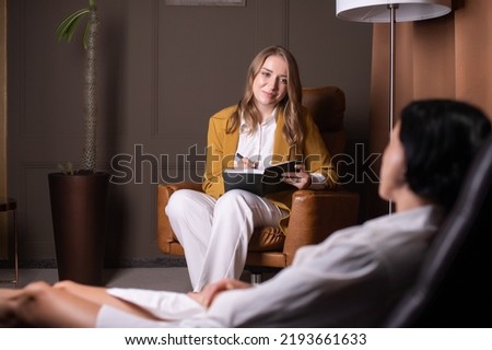 A female psychologist sits in a chair and listens to a client