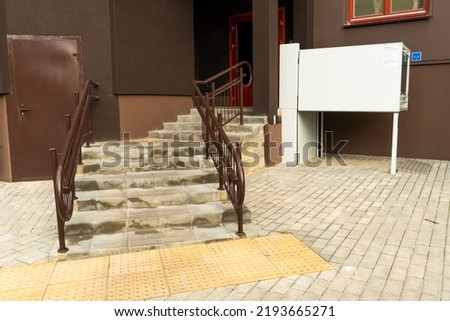 A modern entrance of a residential building equipped with a mechanism for lifting a wheelchair. Lifting ramp with a mechanism for people with disabilities