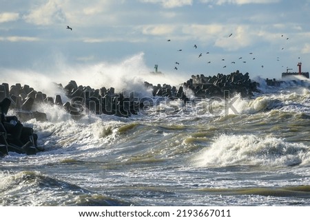 Big waves created during stormy weather crash against the breakwater concrete tetrapods Royalty-Free Stock Photo #2193667011