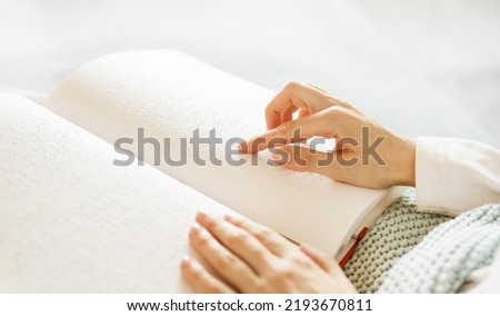 Poorly seeing woman learning Braille book. A person with blindness touches and reads with his hands.