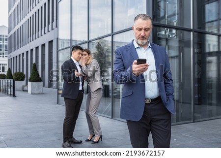 Two colleagues are gossiping at background behind the boss. workmate about bullying problem at work place in office in the break outside Male Coworkers employees man and woman Whispering Behind Back Royalty-Free Stock Photo #2193672157