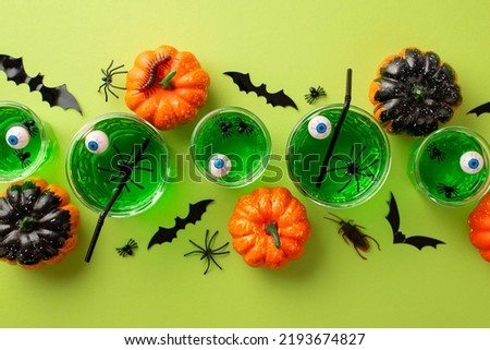 Halloween concept. Top view photo of green floating eyeball punch in glasses spiders bat silhouettes pumpkins spooky insects cockroach and centipede on isolated light green background Royalty-Free Stock Photo #2193674827