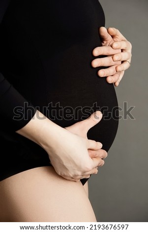 man and woman hands hugging pregnant belly