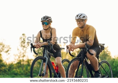 Sporty young woman and man on bicycles during weekend cycle ride. Wearing sports clothes and helmets. Traveling by bicycle. Sports lifestyle. Posing on their bikes during a sunset. Royalty-Free Stock Photo #2193680231