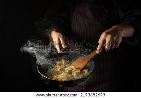 Cooking fresh vegetables and noodles. The cook flips food in a hot frying pan. Thai street food Royalty-Free Stock Photo #2193682693