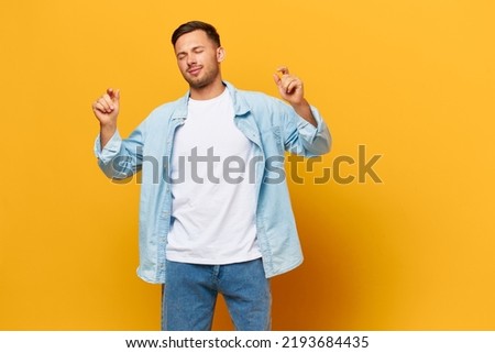 Happy relaxing tanned handsome man in blue basic t-shirt dance enjoy cool day posing isolated on orange yellow studio background. Copy space Banner Mockup. People emotions Lifestyle concept