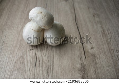 Whole mushrooms heap isolated on wooden background. Sliced champignons, isolated on light wooden background. Champignons, close-up, isolated on wooden background. High resolution image