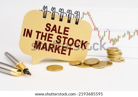 Business concept. On the table are coins, a pen, a graph and a sign with the inscription - Sale in the stock market
