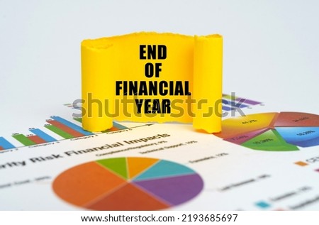 Business concept. Against the background of graphs and charts, a yellow paper plate with the inscription - END OF FINANCIAL YEAR